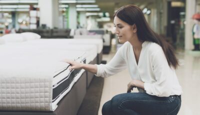 A Richtige Matratze auswählenChooses A Mattress In A Store. She Sits Next To Him And